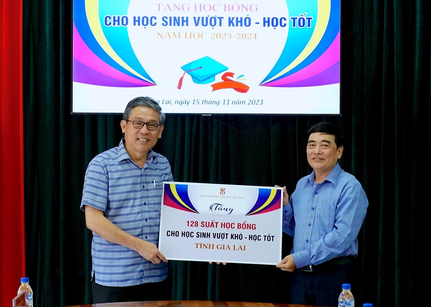 Giám đốc Sở GD-ĐT Lê Duy Định (bìa trái) nhận bảng tặng học bổng tượng trưng từ đại diện Nhà xuất bản Giáo dục Việt Nam. Ảnh: Mộc Trà