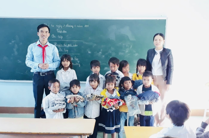 Thầy giáo Trương Công Hương (bìa trái)-giáo viên làm Tổng phụ trách Đội Trường Tiểu học và THCS Kim Đồng tặng quà cho học sinh khó khăn. Ảnh: M.N