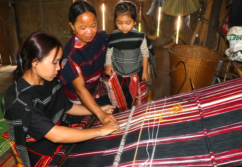 Tranh thủ những lúc nông nhàn, sớm tối, các bà, các mẹ ở làng Pốt, xã Song An, thị xã An Khê lại cần mẫn hướng dẫn con em mình dệt vải. Ảnh: Ngọc Minh