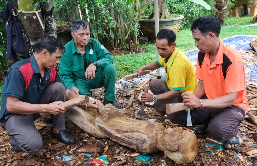 Nghệ nhân Ưu tú Ksor Krôh (thứ 2 từ trái qua) hướng dẫn các học viên về kỹ thuật đẽo tượng nhà mồ. Ảnh: H.N