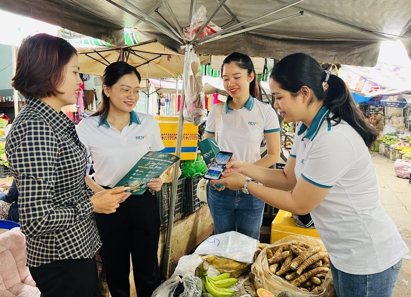 Nhân viên BIDV Gia Lai hướng dẫn tiểu thương phường Hoa Lư (TP. Pleiku) về dịch vụ thanh toán không dùng tiền mặt. Ảnh: P.L